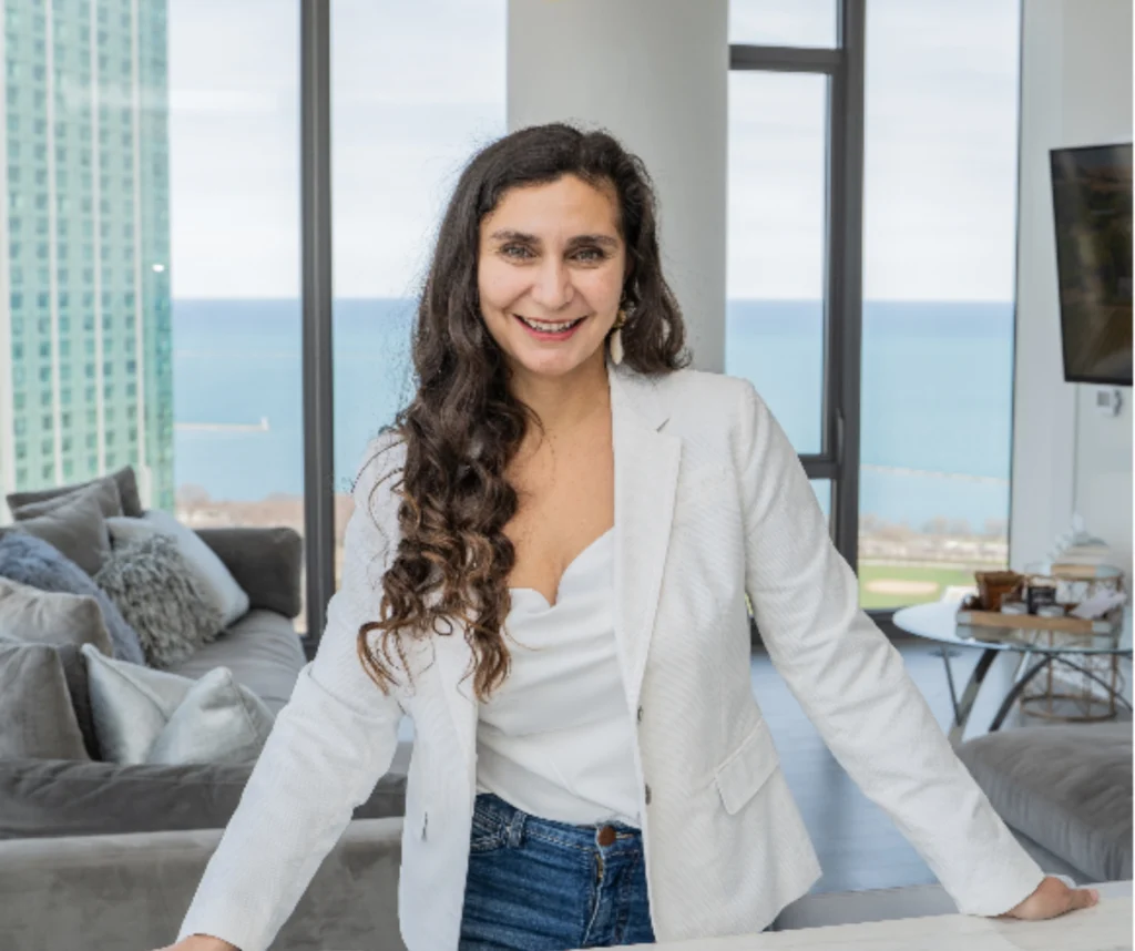 Mira Kelley smiling in a white blazer in a bright living room
